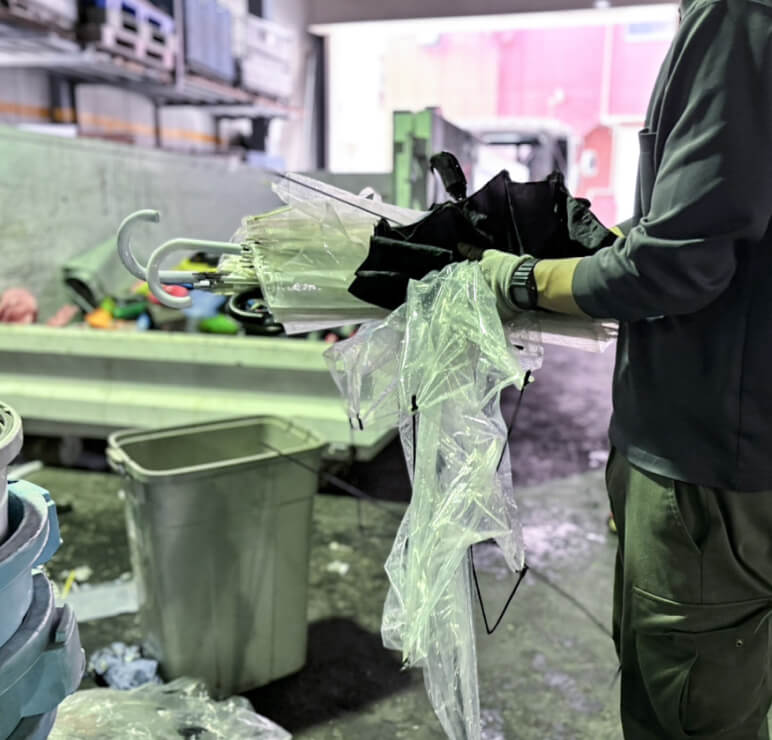 作業員が傘やプラスチック類の廃棄物を仕分けしている様子